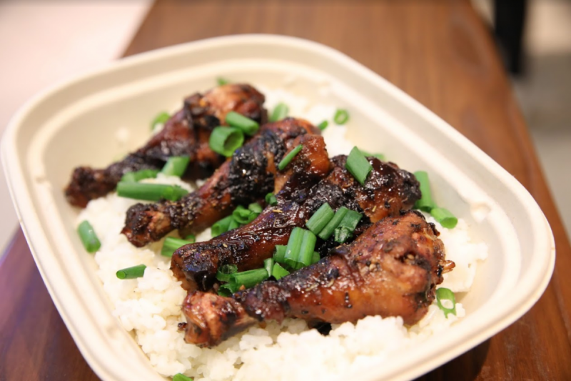 Four wings served with scallions and rice in a compostable serving container
